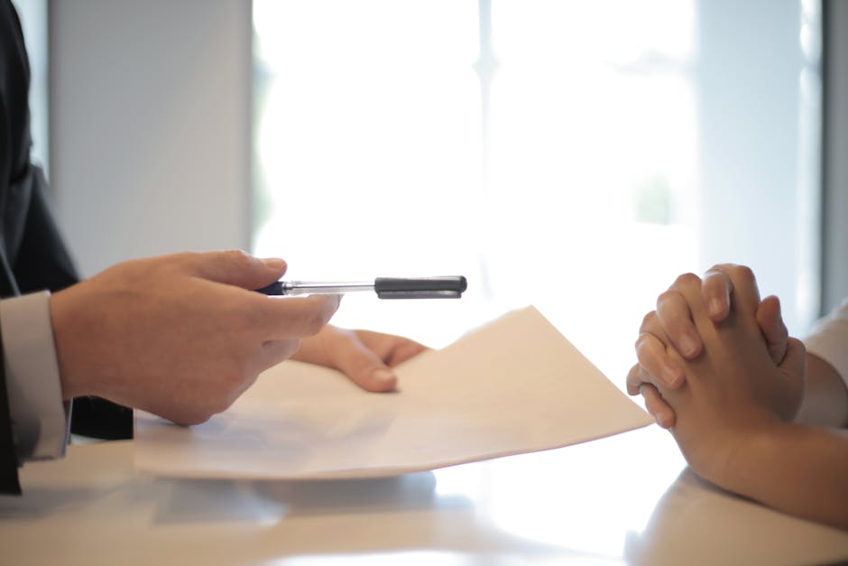 A person is signing papers with someone else.