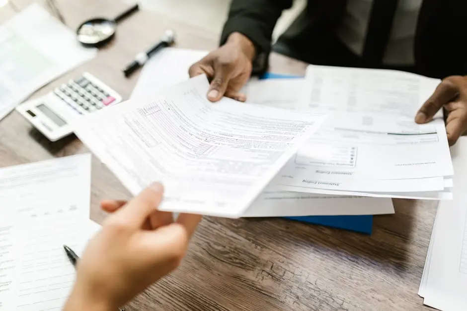 A person is pointing to an envelope on top of papers.
