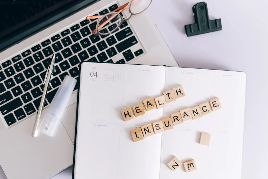 A notebook with the words health insurance spelled out in scrabble tiles.